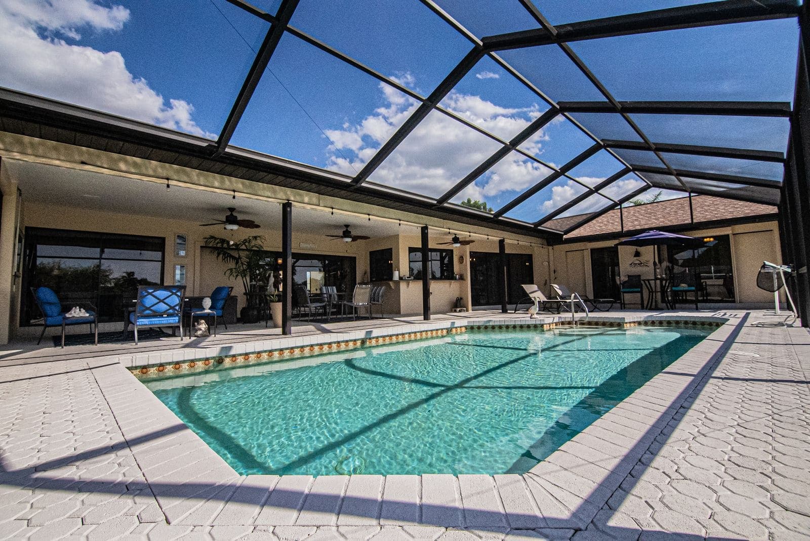 In-ground pool with a paver deck under a screen enclosure attached to a covered lanai in Jacksonville, FL